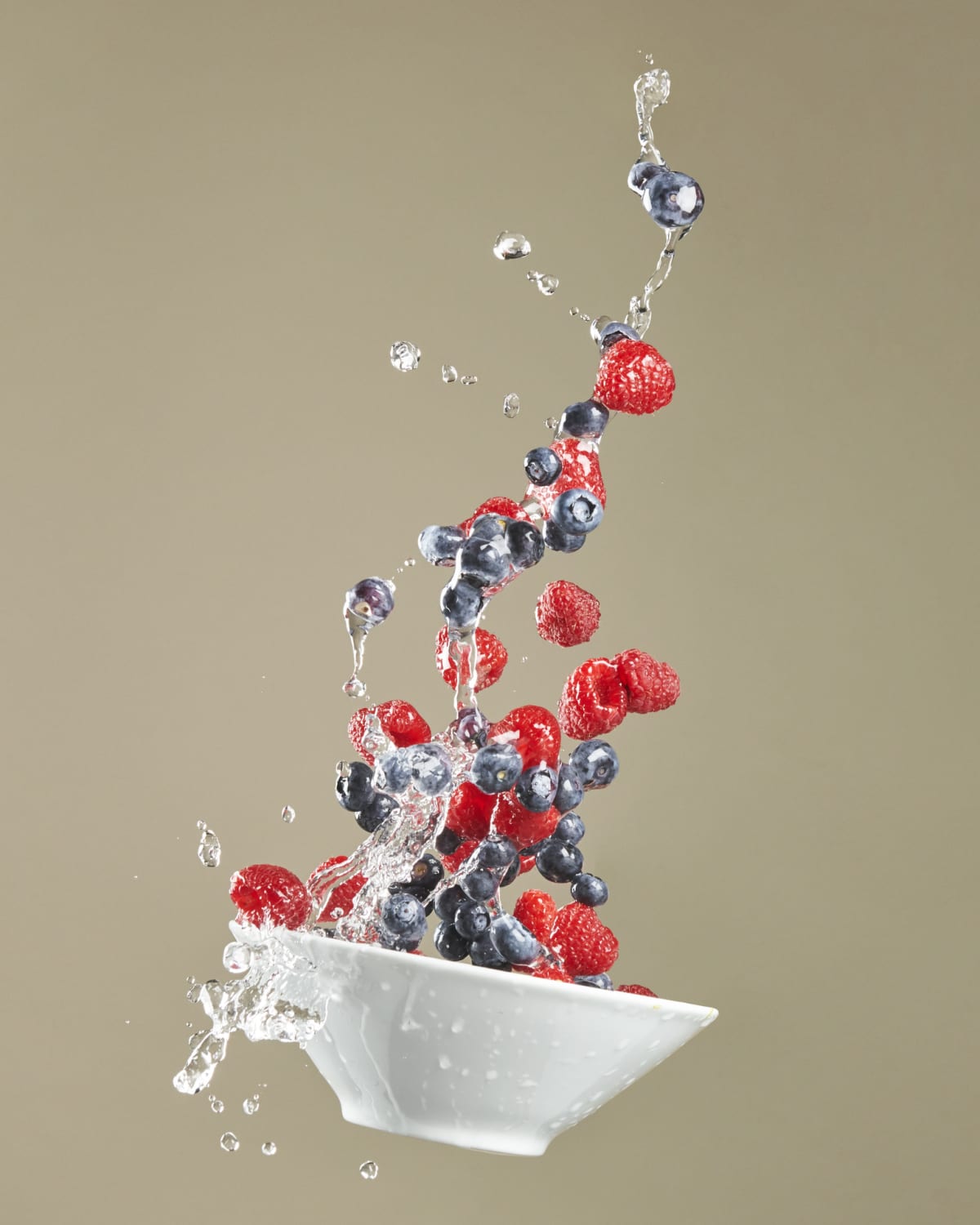 A bowl of blueberries is frozen in motion mid-air