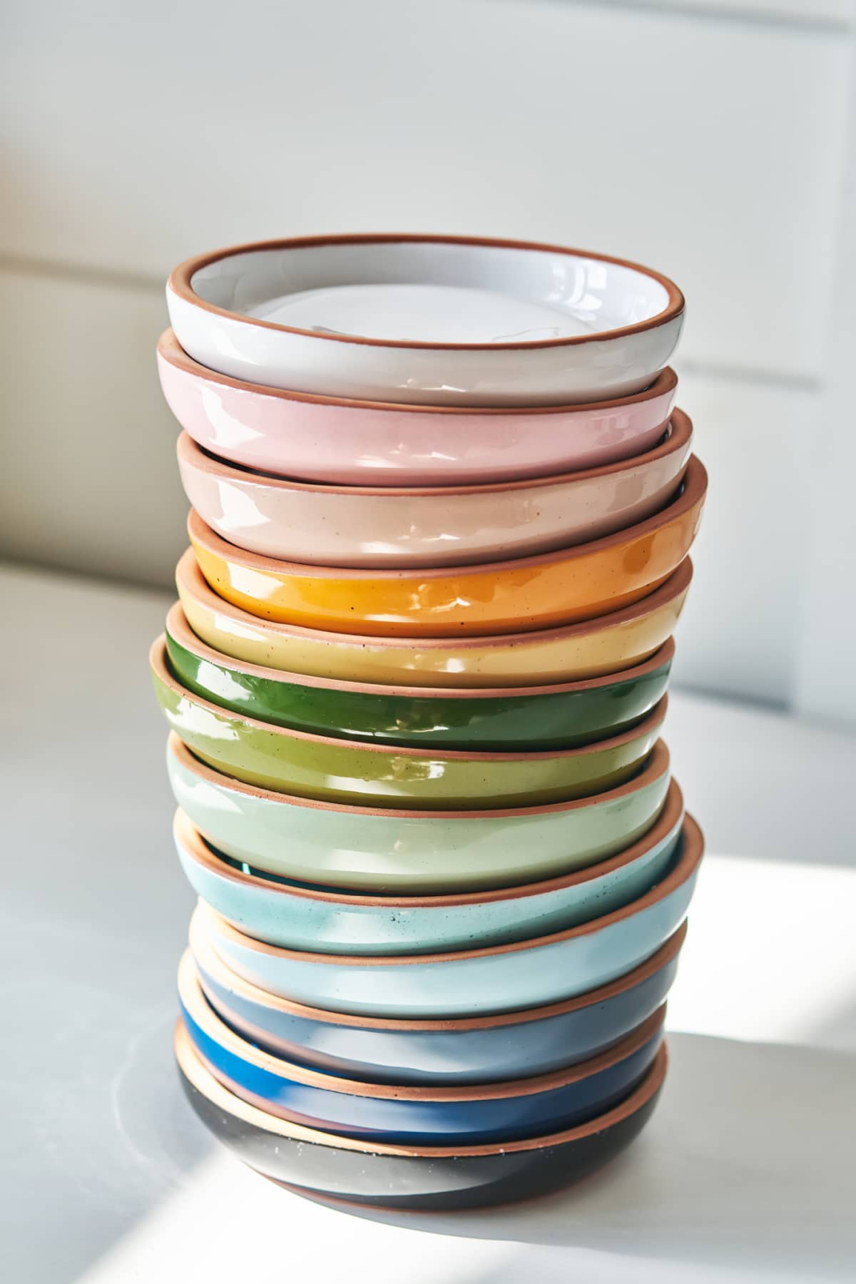 A stack of bright multicolored ceramic plates on a white background.