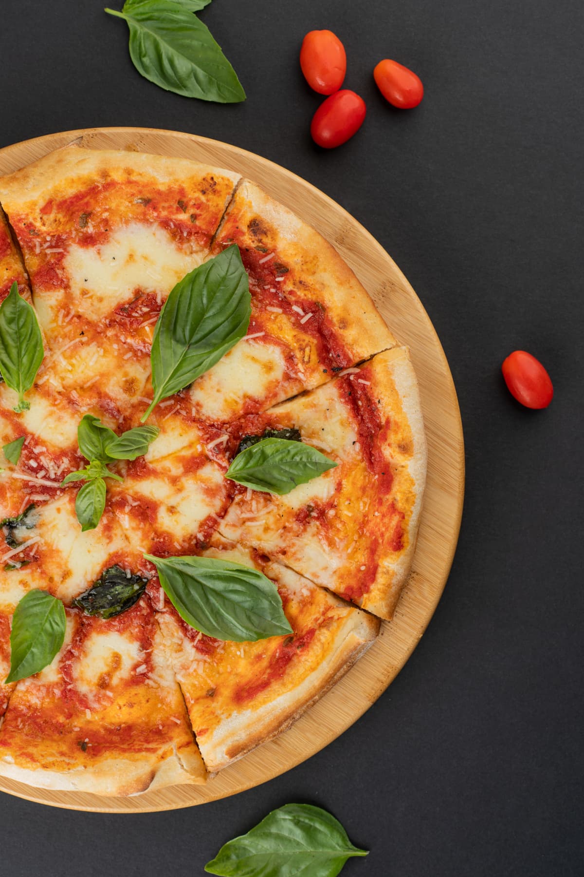 Italian food: delicious pizza with mozzarella and cherry tomatoes shot from above on dark grey background vertical shot