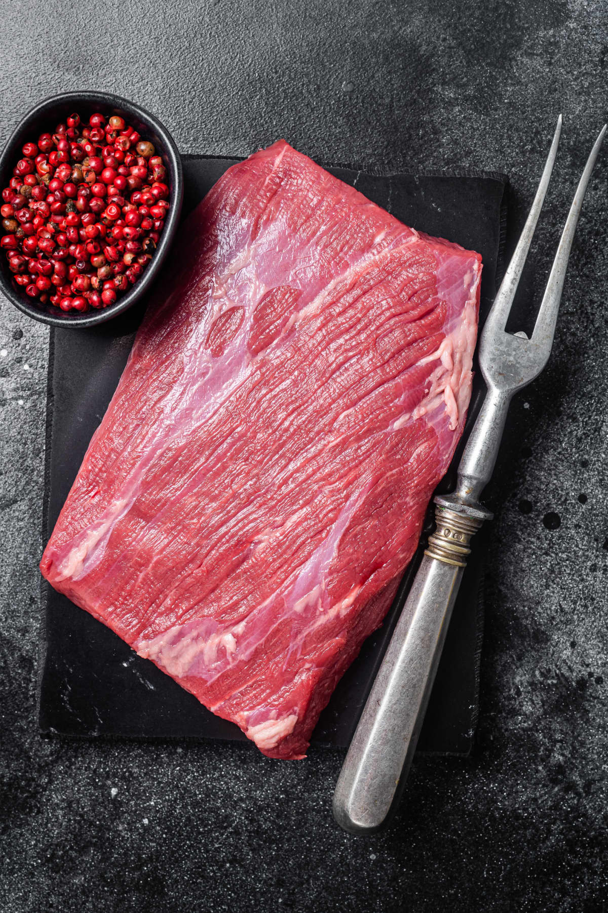 Raw flank steak with a fork