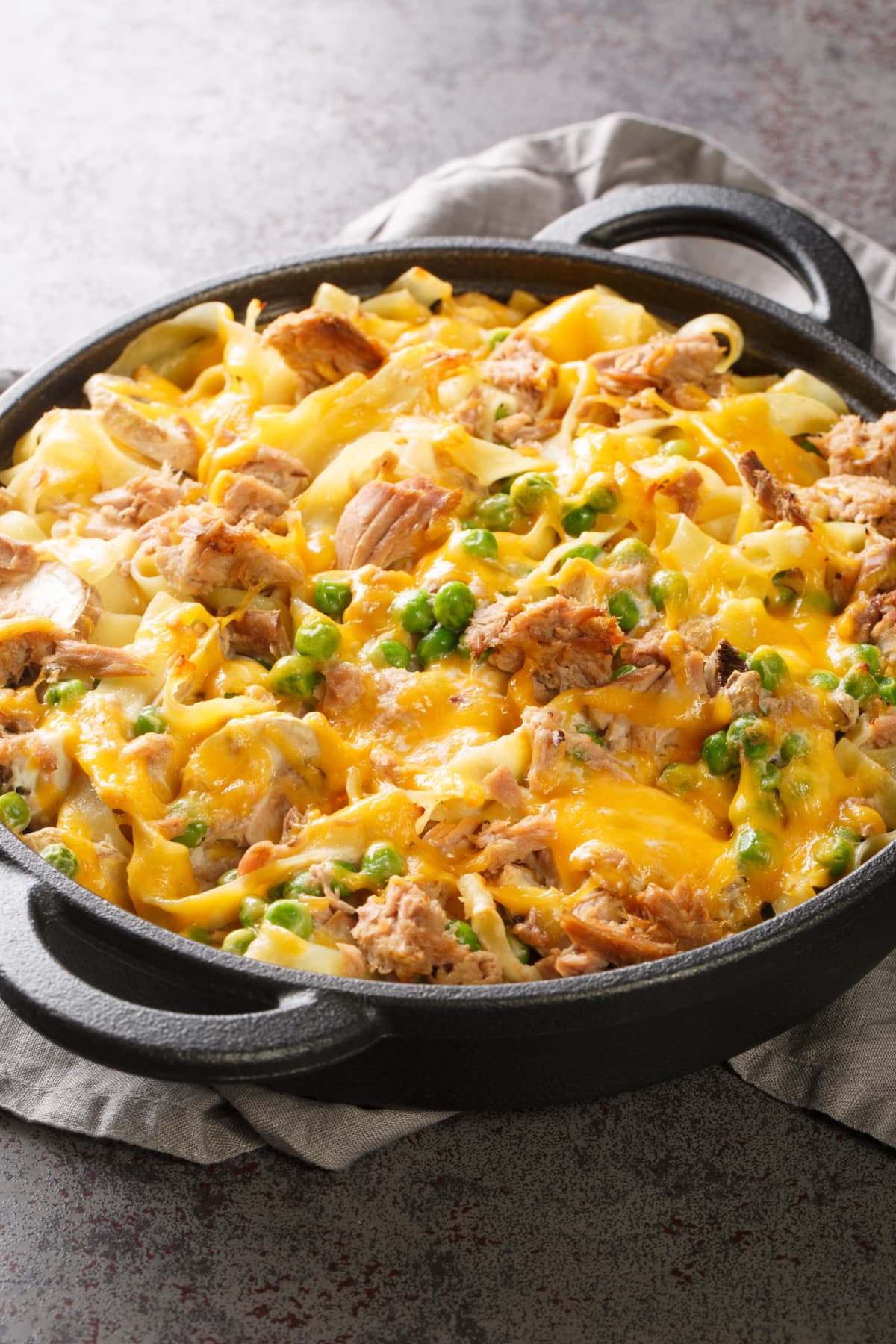Casserole with noodles, meat, peas, and cheese in cast iron pan