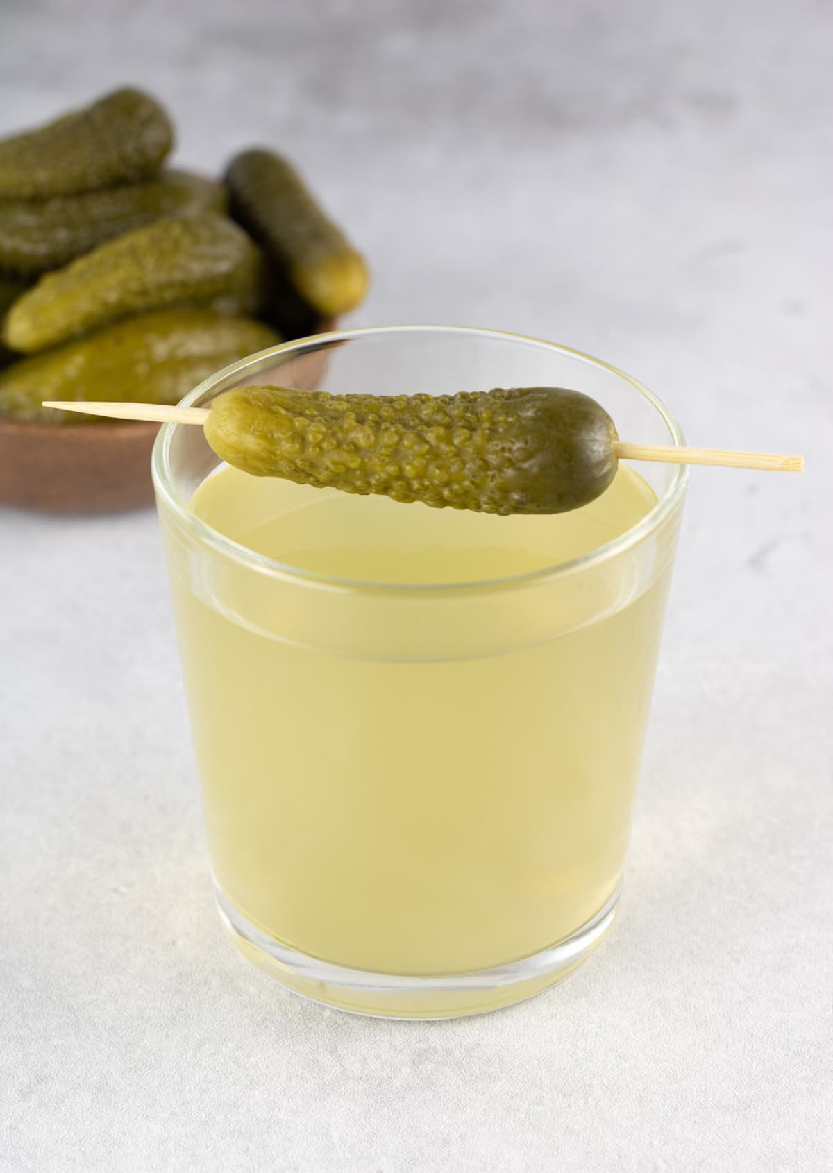 Pickle juice or brine in a glass and jar of pickled cucumbers on a white background. Copy Space.