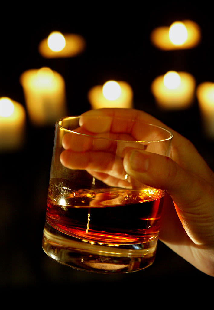 A person holding a glass of whisky