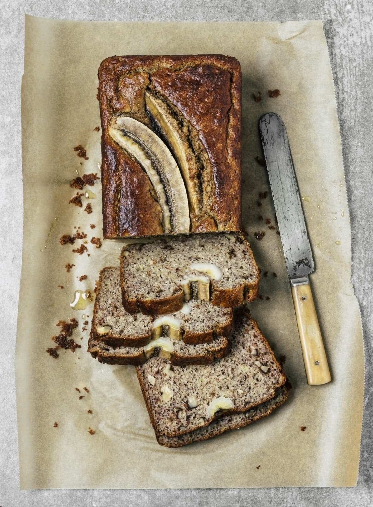Banana bread sliced on parchment paper with knife