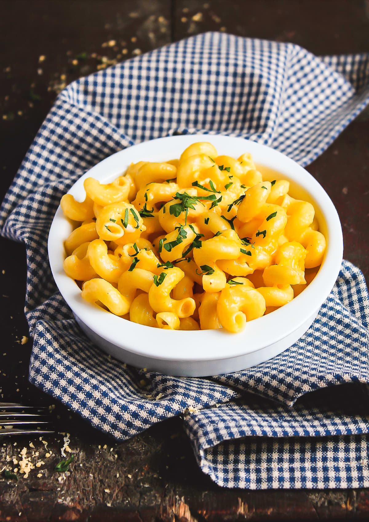 Mac and cheese in a white bowl resting on checkered cloth