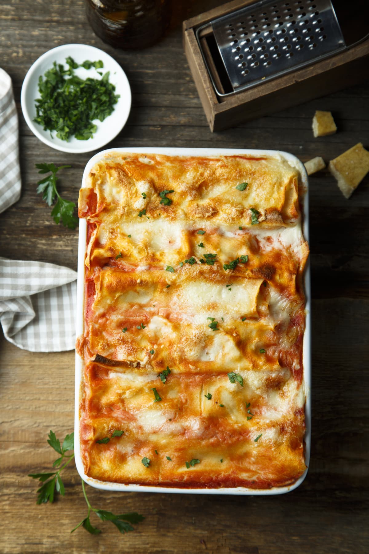 Baked lasagna in a white tray on a wooden table.