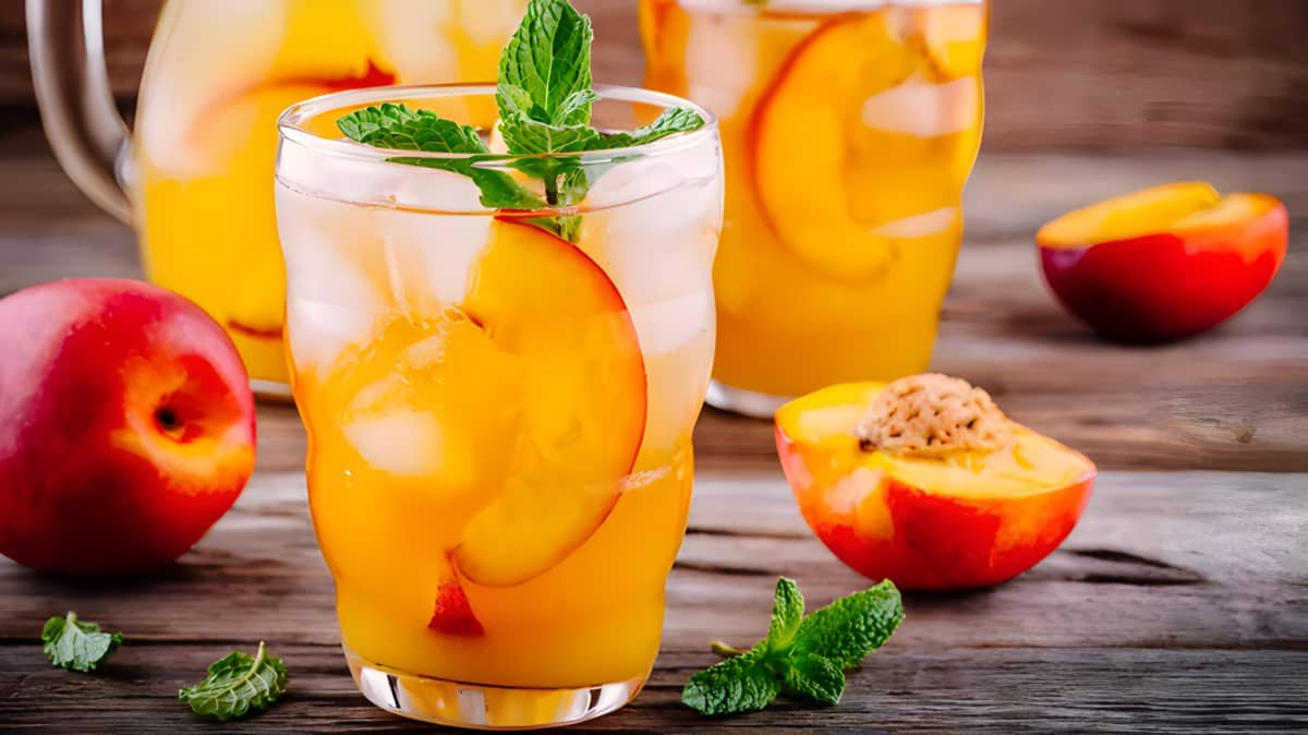 Tall glass of peach iced tea garnished with mint