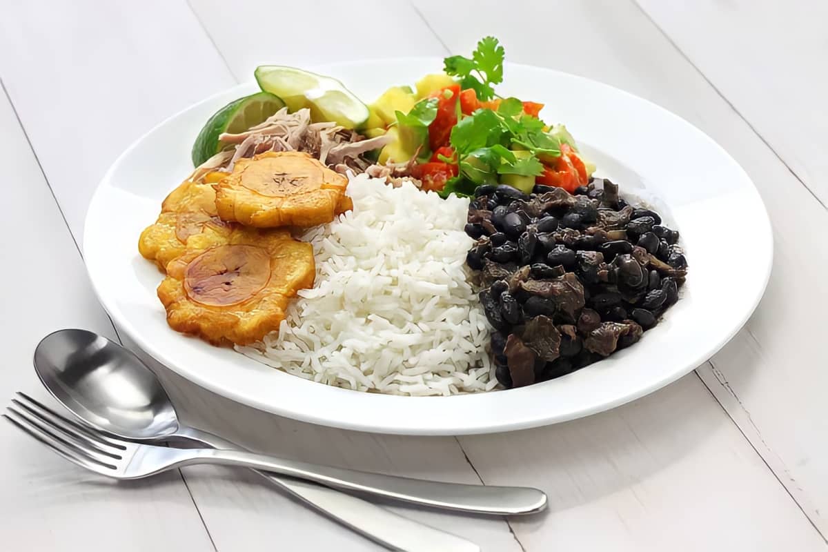 A plate of rice and beans with an avocado and tomato salad