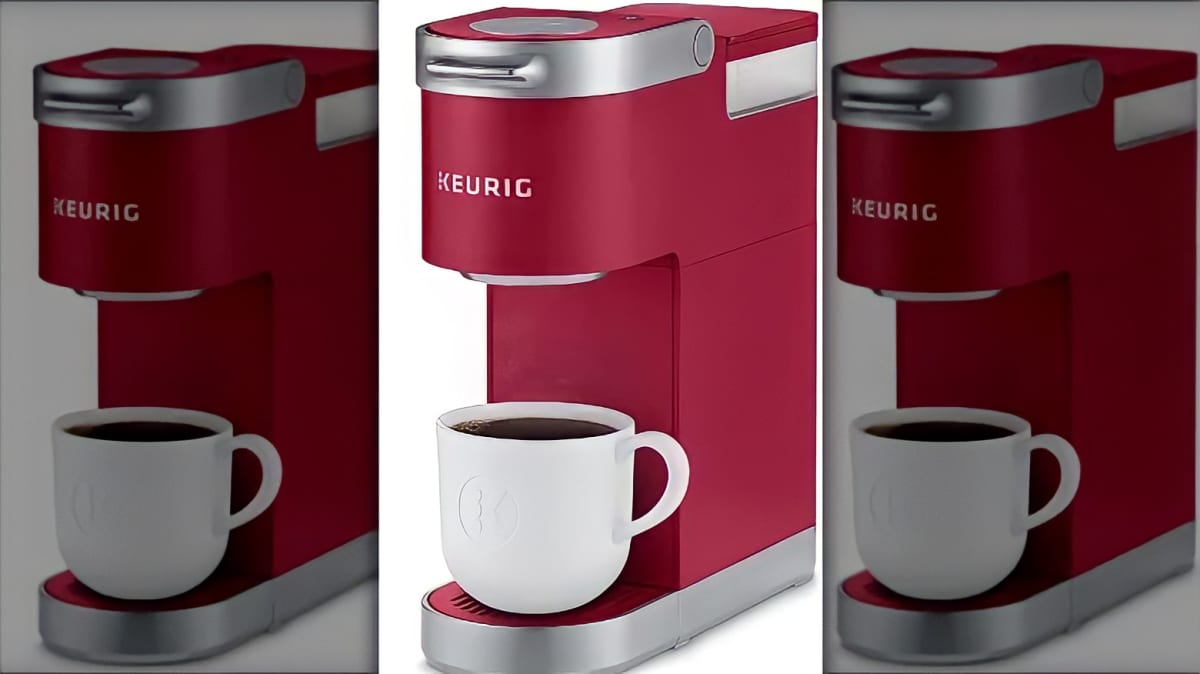 A red Keurig machine brewing coffee into a white coffee mug