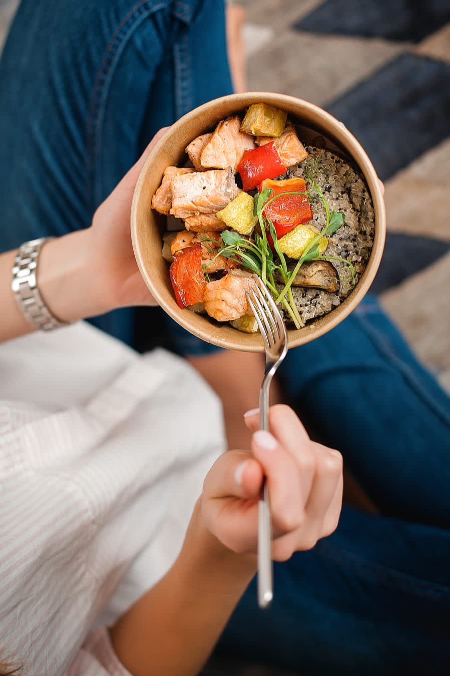Person holding a bowl of healthy food items