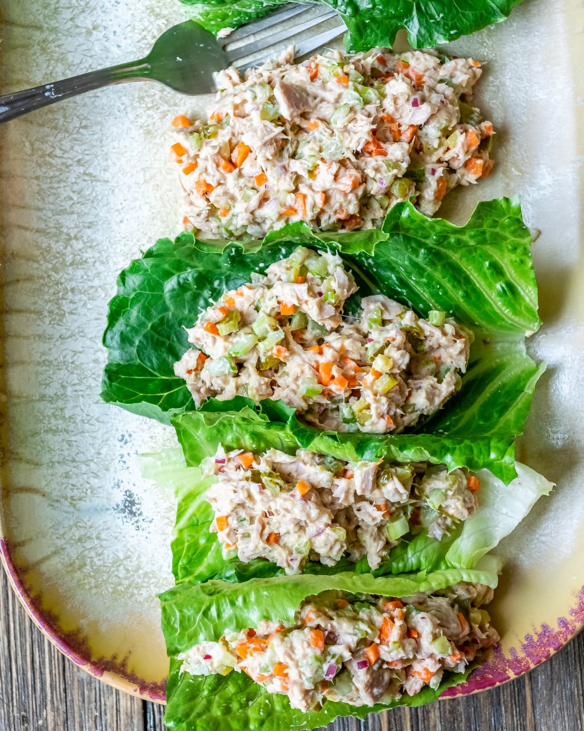 Tuna salad lettuce wraps and a fork in a serving plate on wooden table