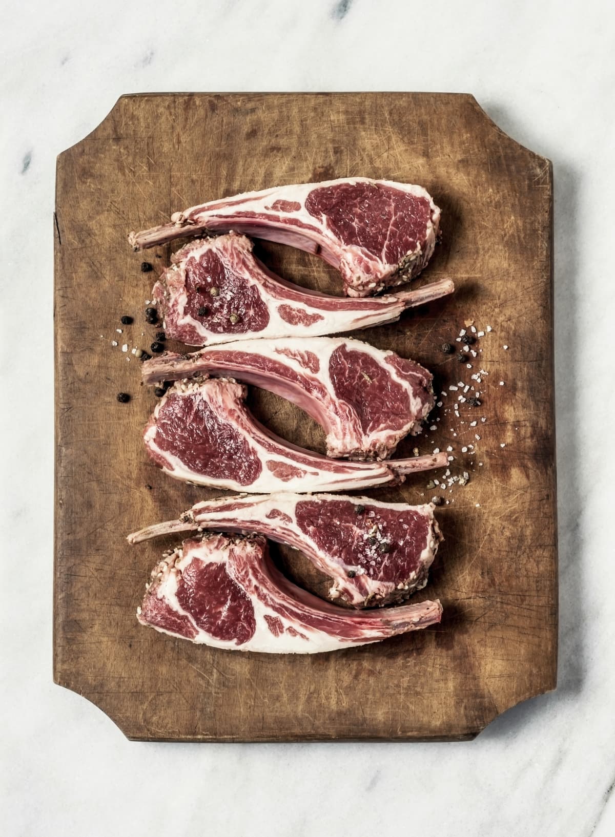 Raw fresh lamb ribs on wooden cutting board on white background