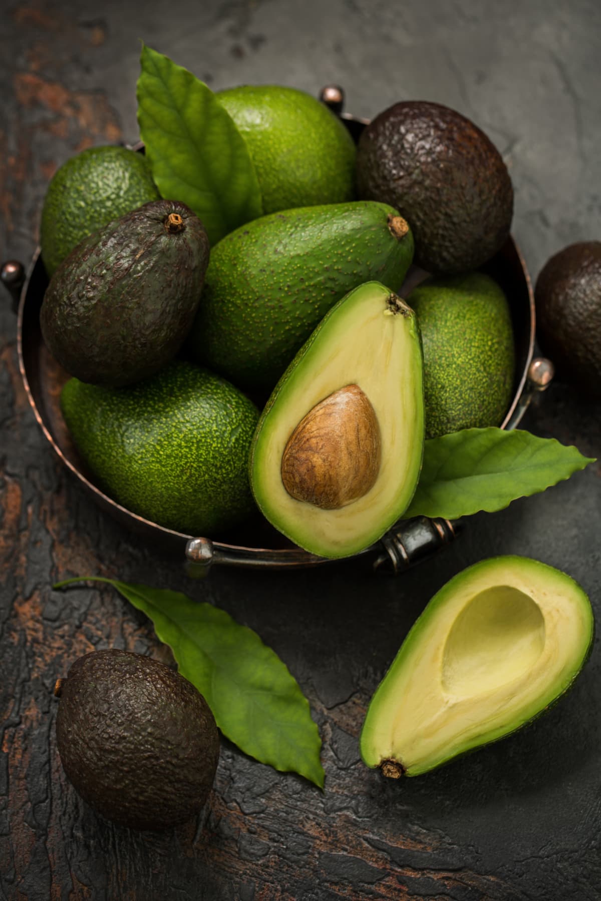 Ripe flying Avocado Hass halves on green background