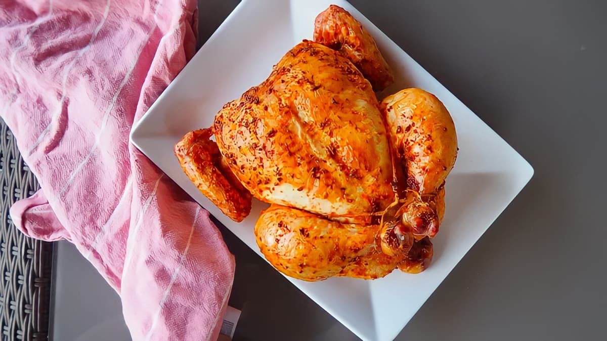 A rotisserie chicken on a white plate