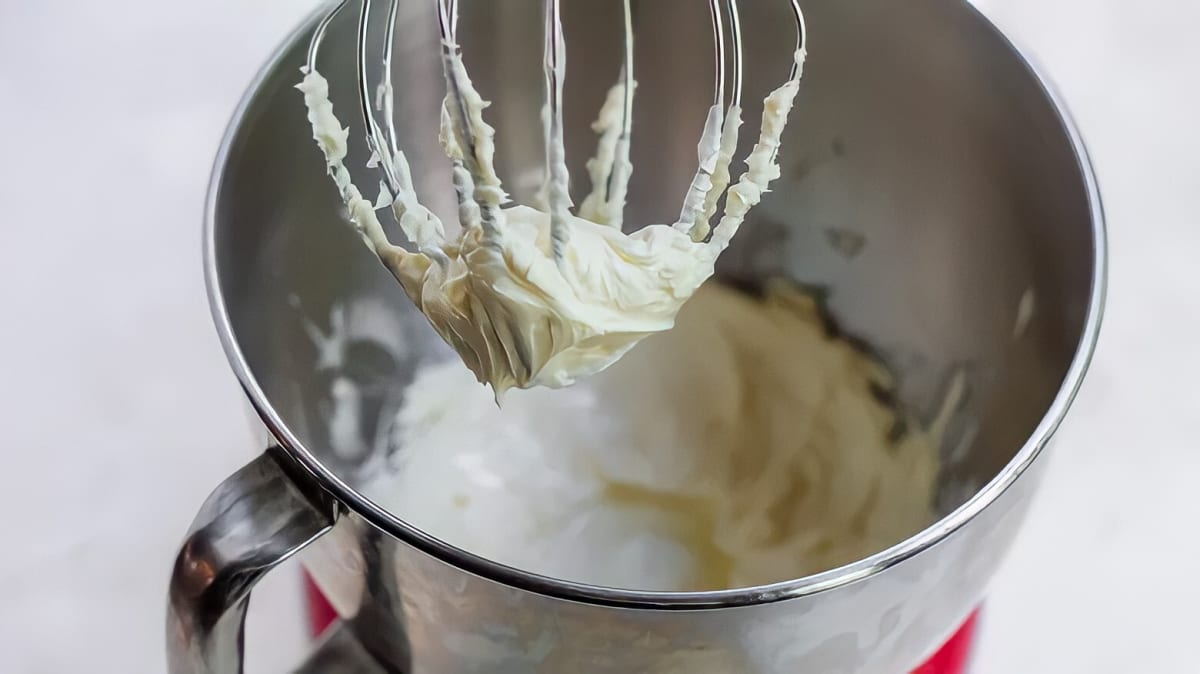 A mixer with frosting on the whisk attachment