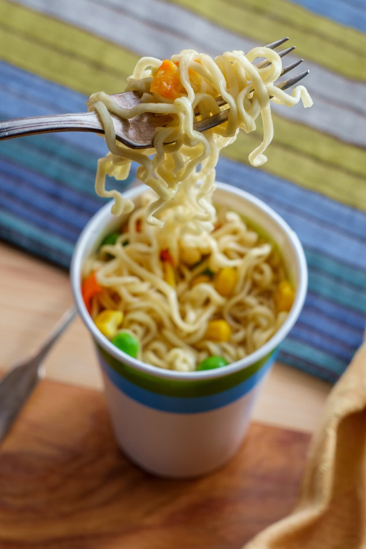 A forkful of noodles being lifted from a cup of instant ramen
