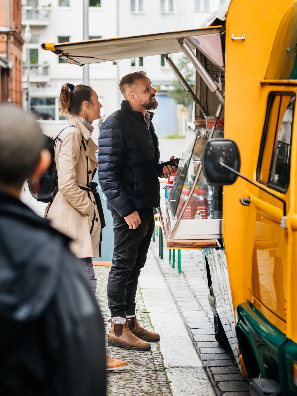 A man ordering something to eat from a food truck after waiting in line in a city street