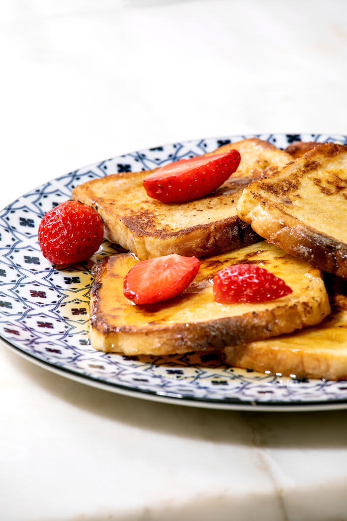 Stockpile of french toasts with fresh strawberries and maple syrup on ceramic plate on white marble table. Close up. (Photo by: Natasha Breen/REDA&CO/Universal Images Group via Getty Images)