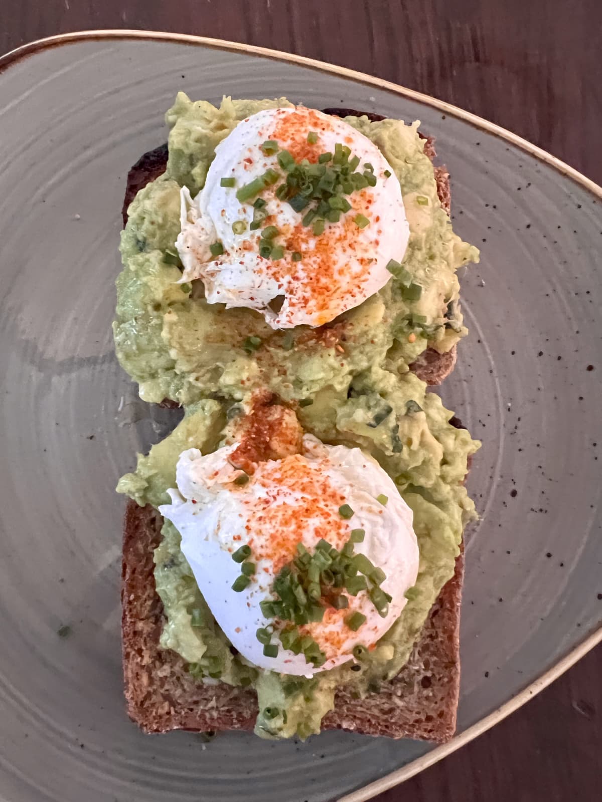 Tasty poached eggs with chives on top of smashed avocado on Nordic style bread