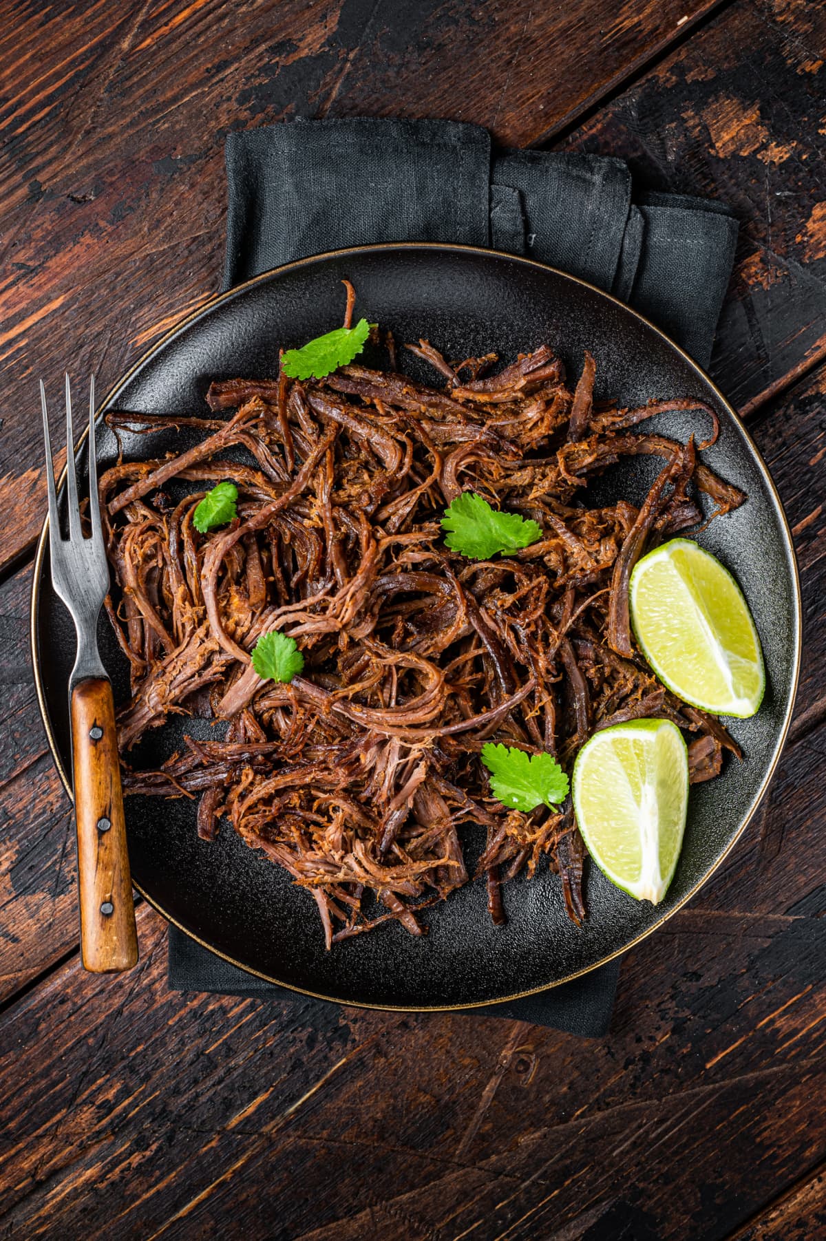 Carnitas in a plate with celery and lime wedges
