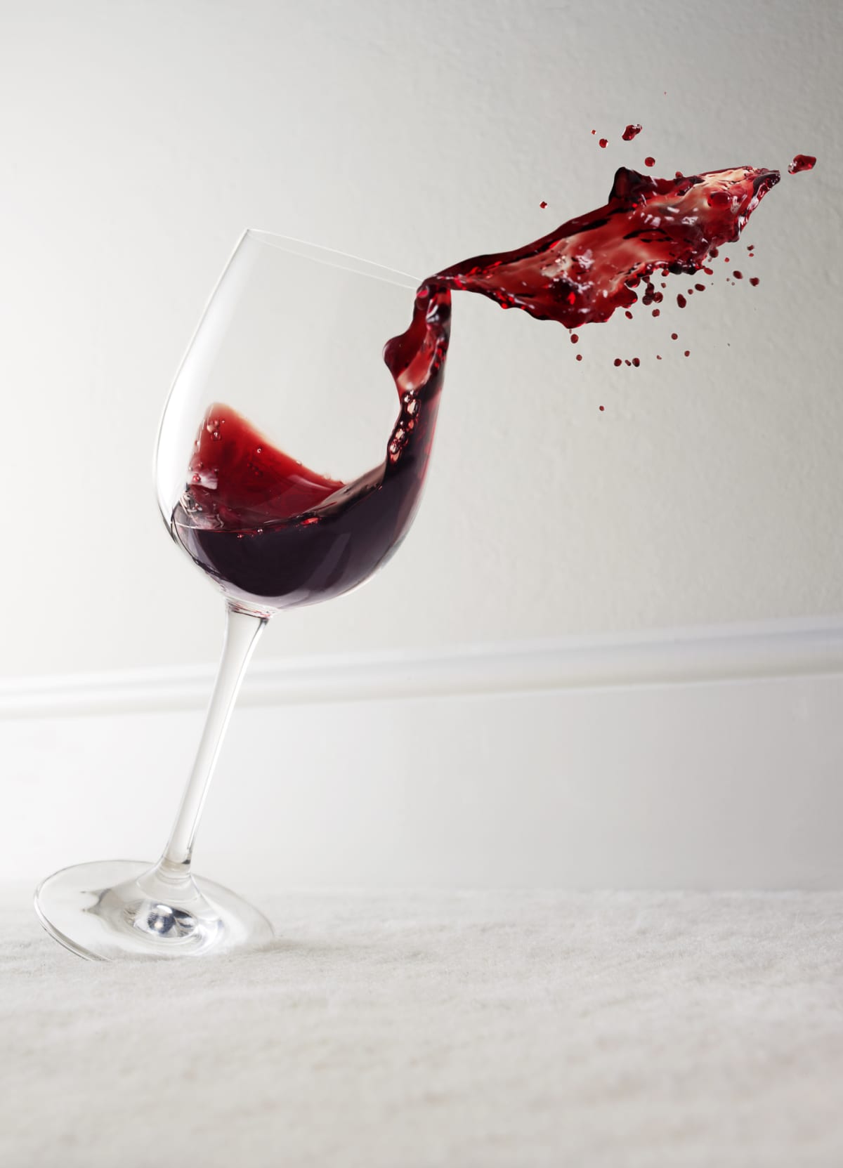 Glass of red wine tipping over and spilling