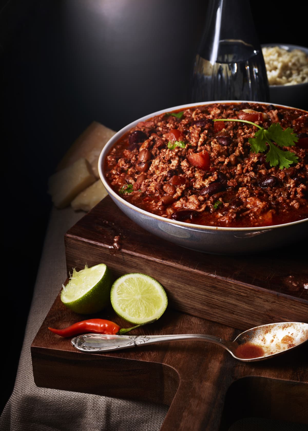 A bowl of chilli con carne with a red chilli and lime