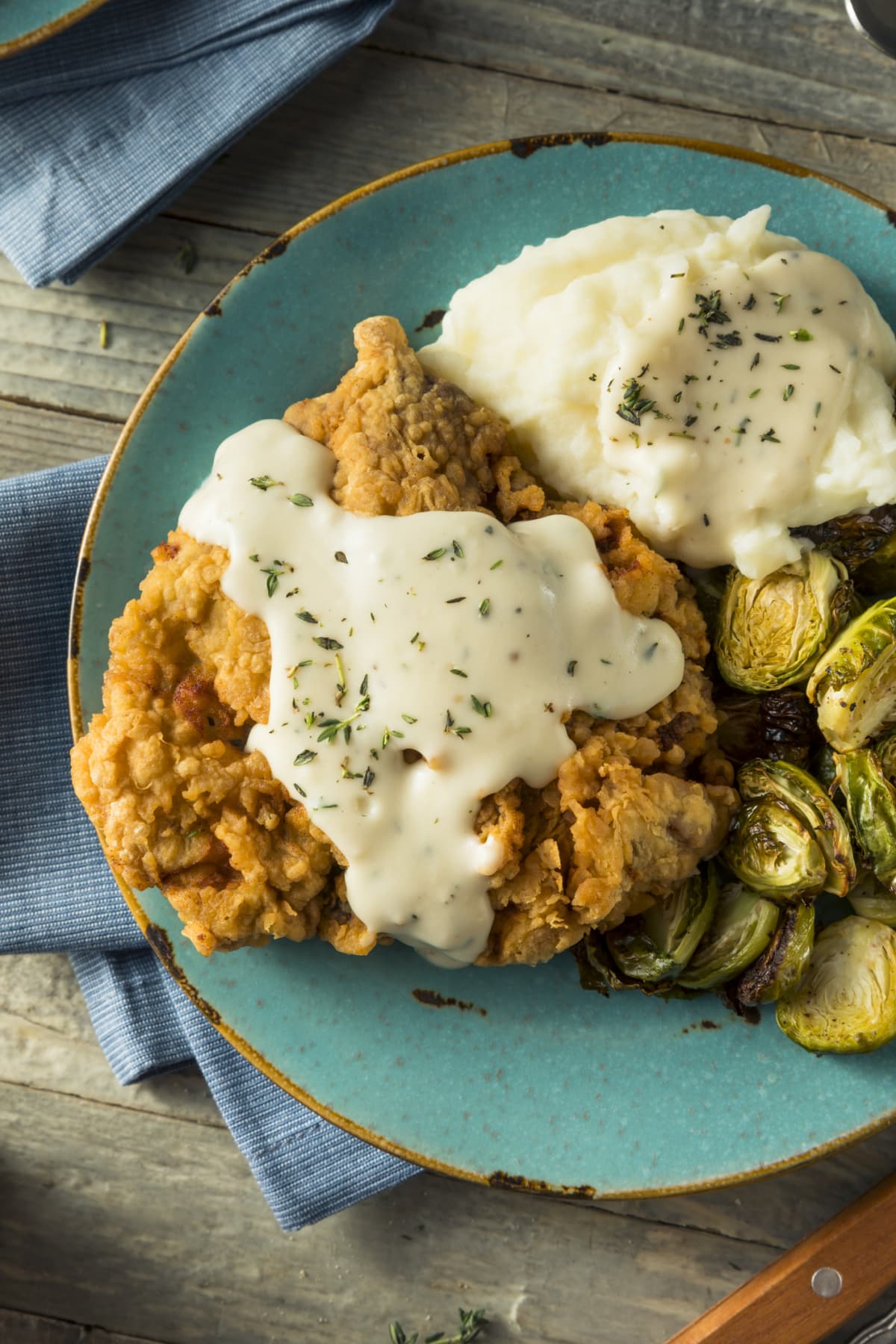 Plate of country fried steak with gravy, mashed potatoes, and Brussels sprouts