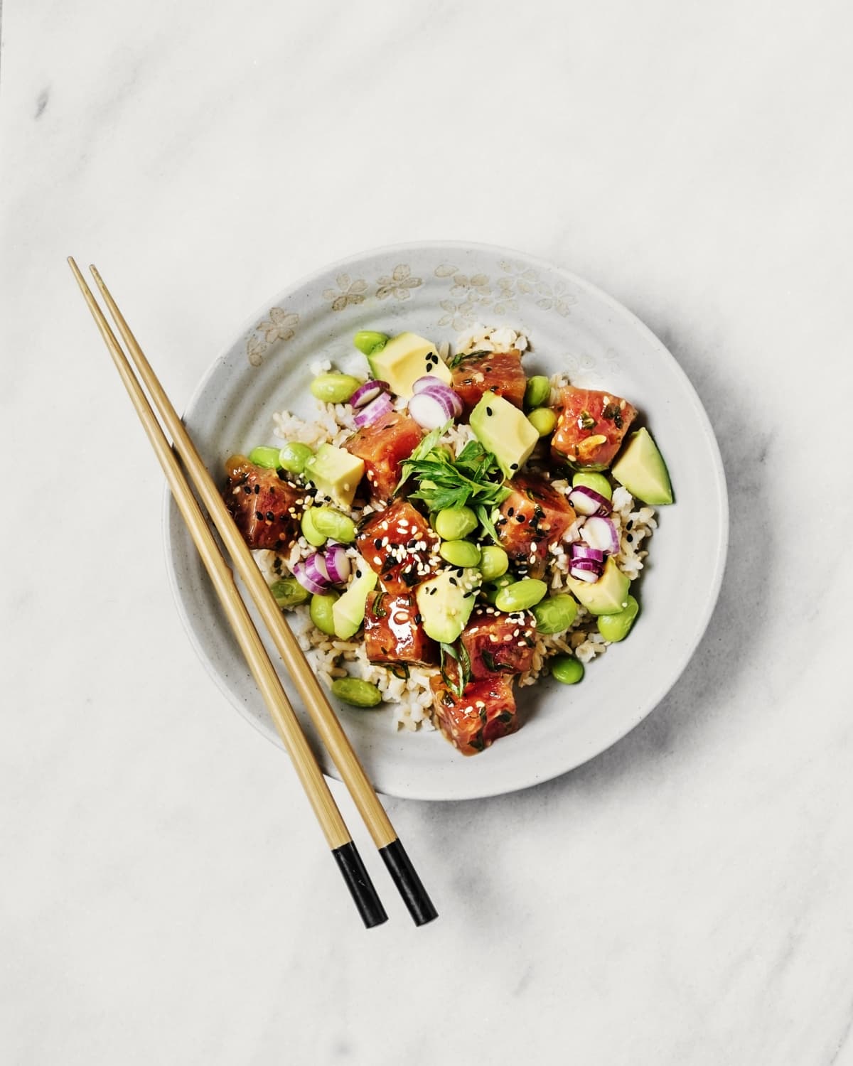 Tuna and avocado poke bowl on white background with chopsticks