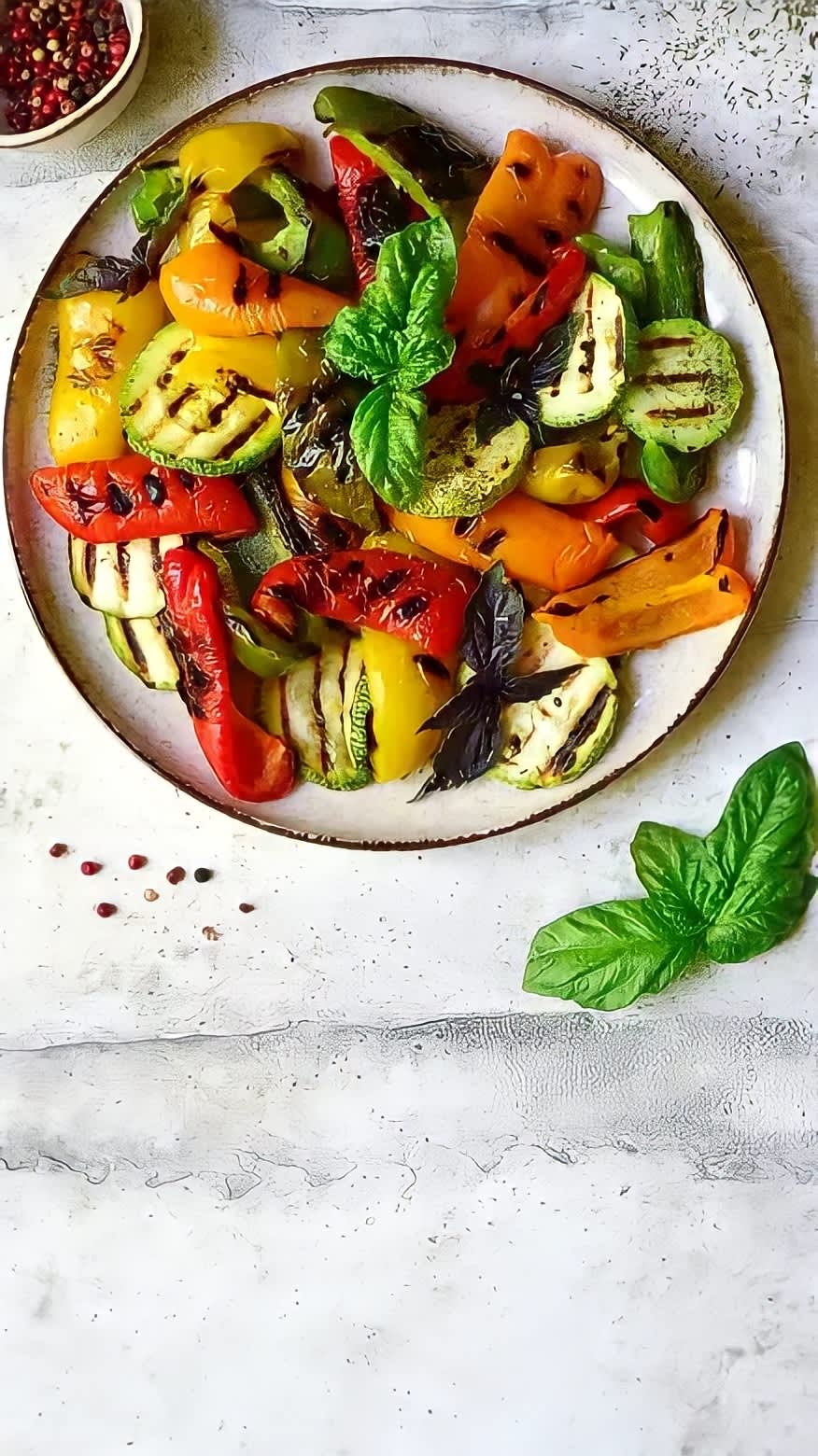 Grilled vegetables on a plate with green garnish and spices on the side
