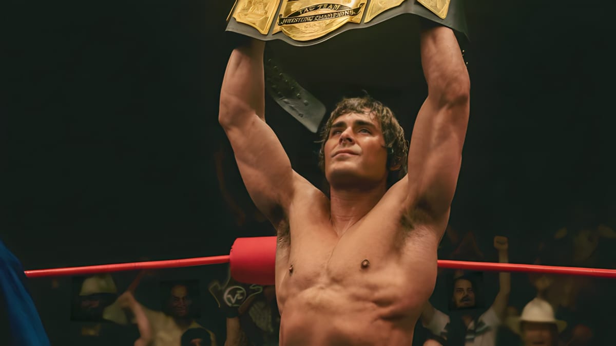 Zac Efron holding up a belt in the iron claw