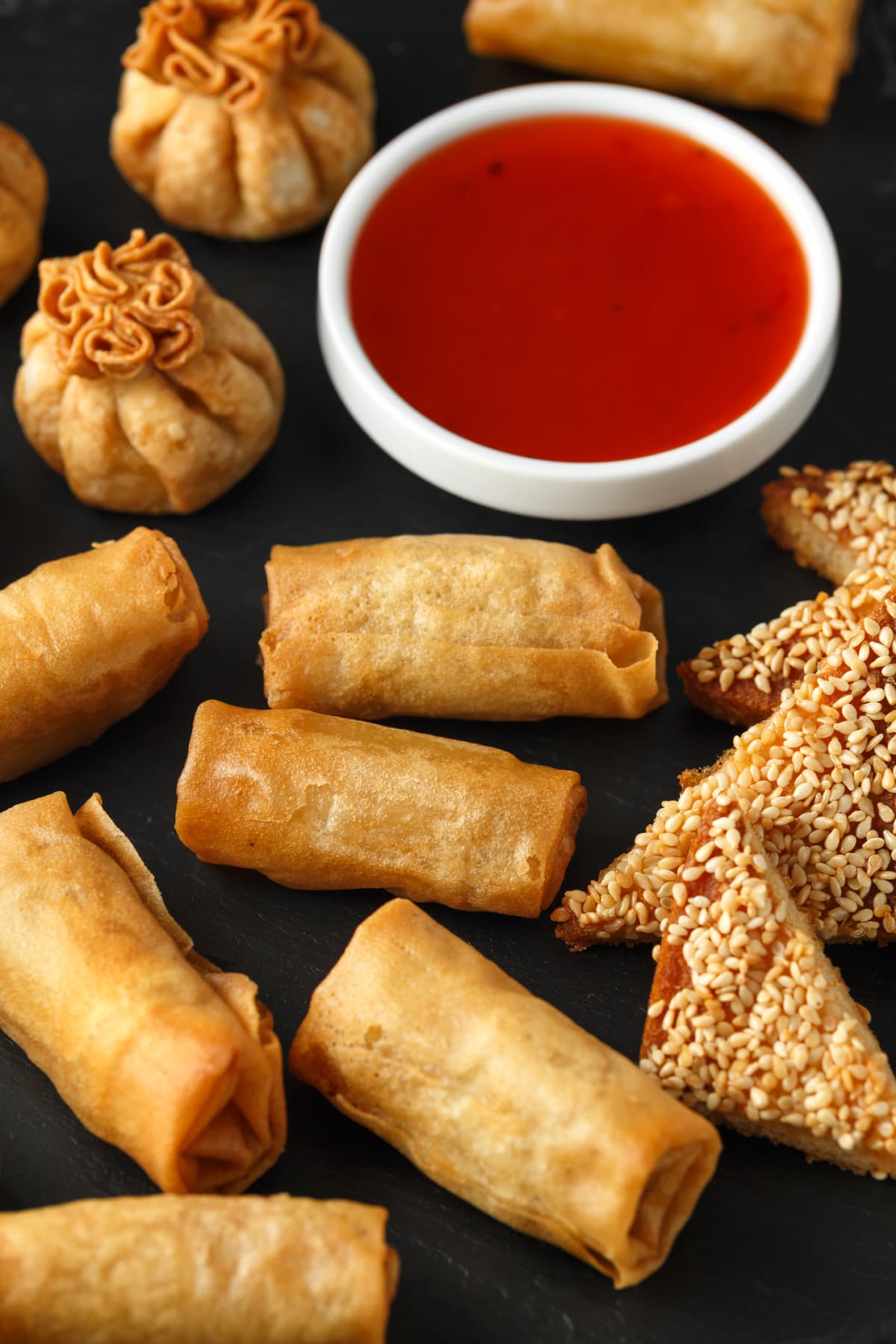 Crispy chicken wontons and vegetable spring rolls with a dish of sweet chili sauce