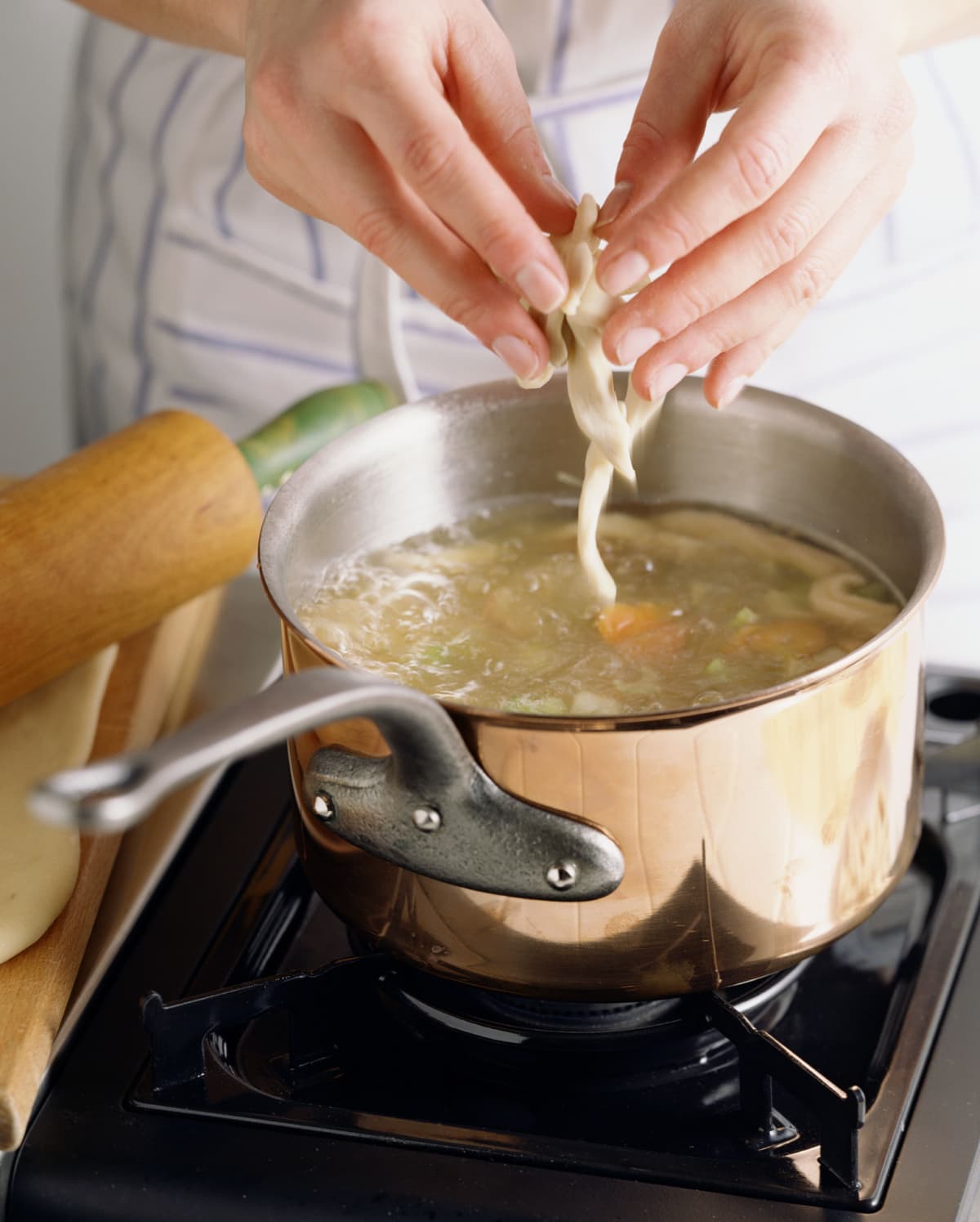 A person adding ingredients to a pot of soup