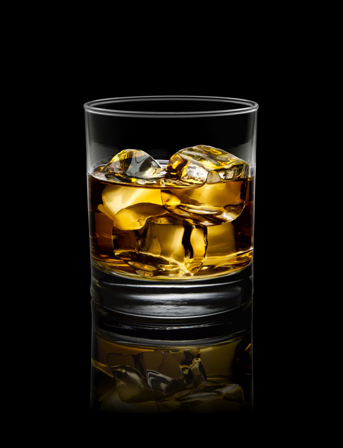  glass of whisky with ice, in a dark background.