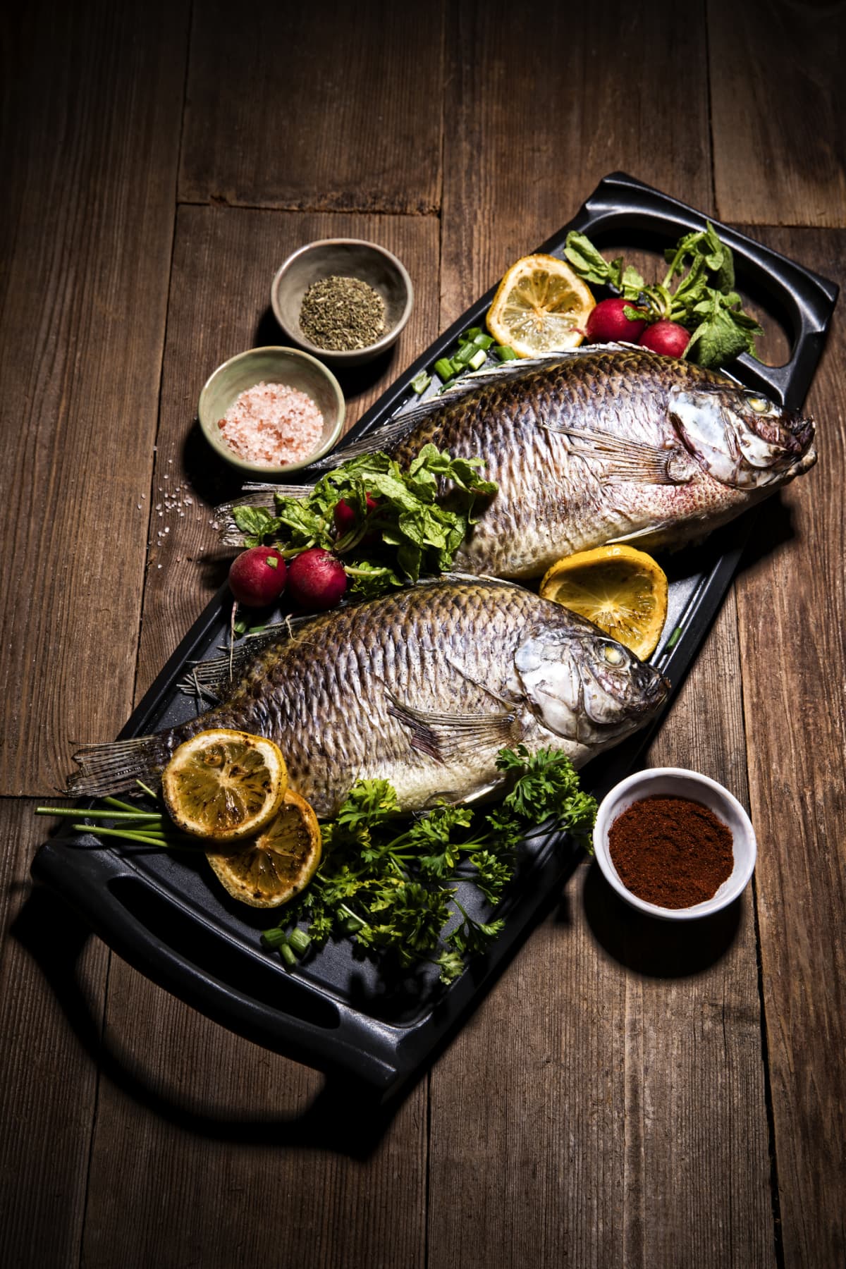 Baked sea Bass fish with arugula, grilled seabass. Black background. Top view.