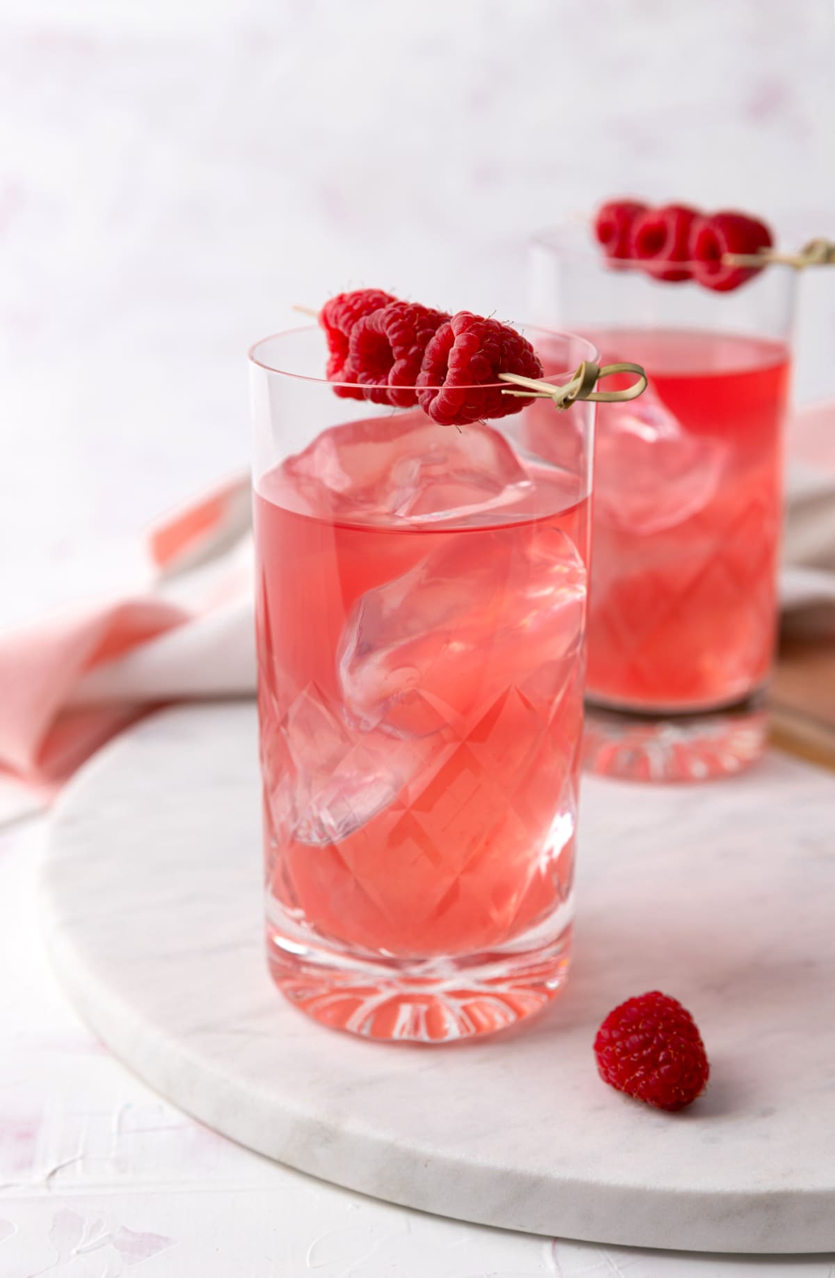 Pink rose cocktails with raspberries in crystal glasses on a table