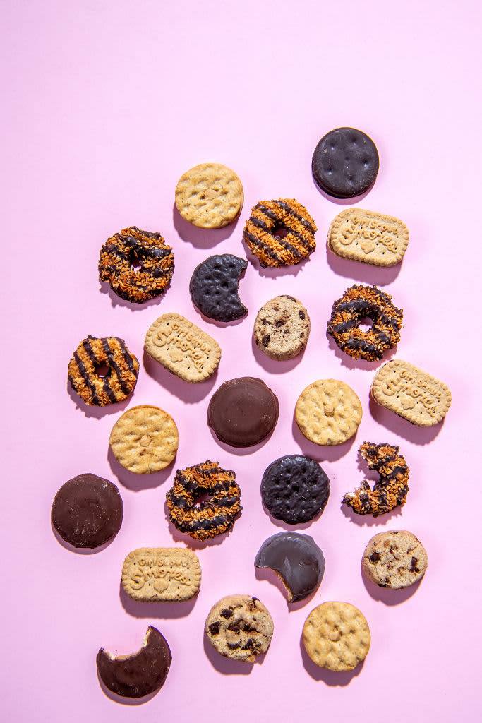 Assorted Girl Scout cookies on a pink background.