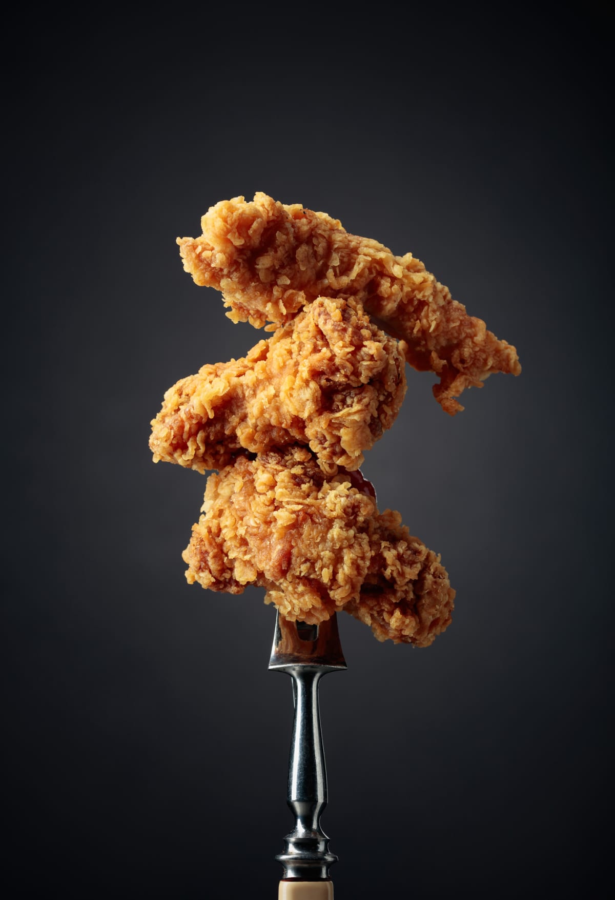 Delicious hot crispy fried chicken on a fork.