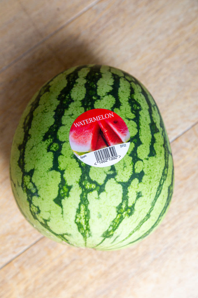 Watermelon with produce sticker on wood