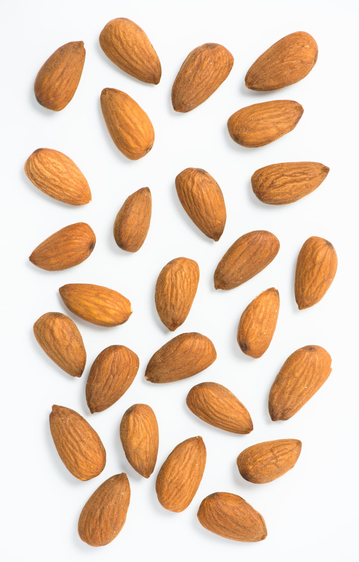 Overhead view of whole almonds arranged on a white background