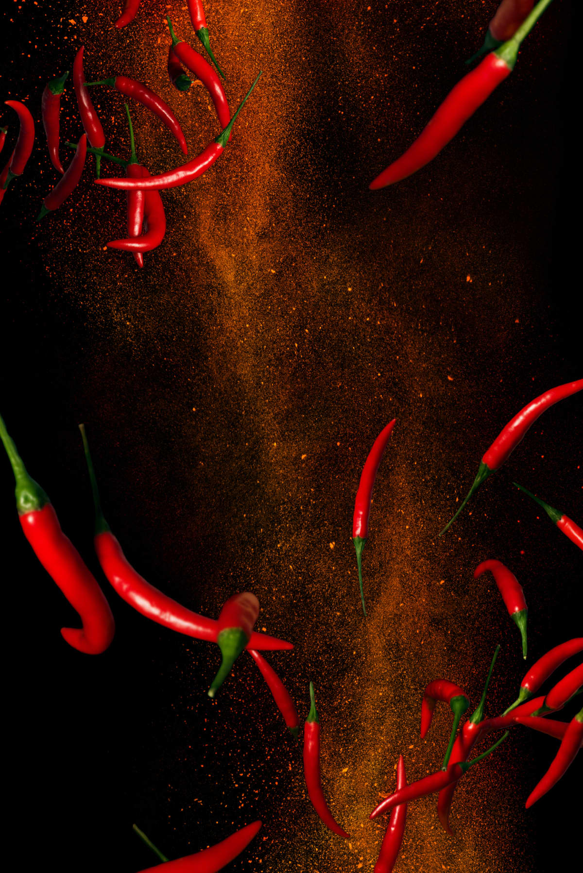 Hot red pepper flakes in flight. Plenty of fresh fruit along with the dry ground powder. Dynamic conceptual photography on a black background