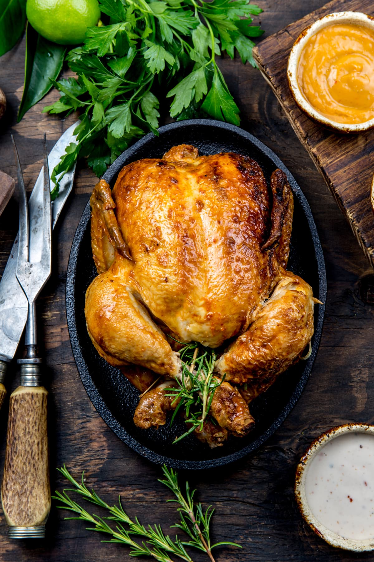 Roasted whole chicken in pot on wooden table