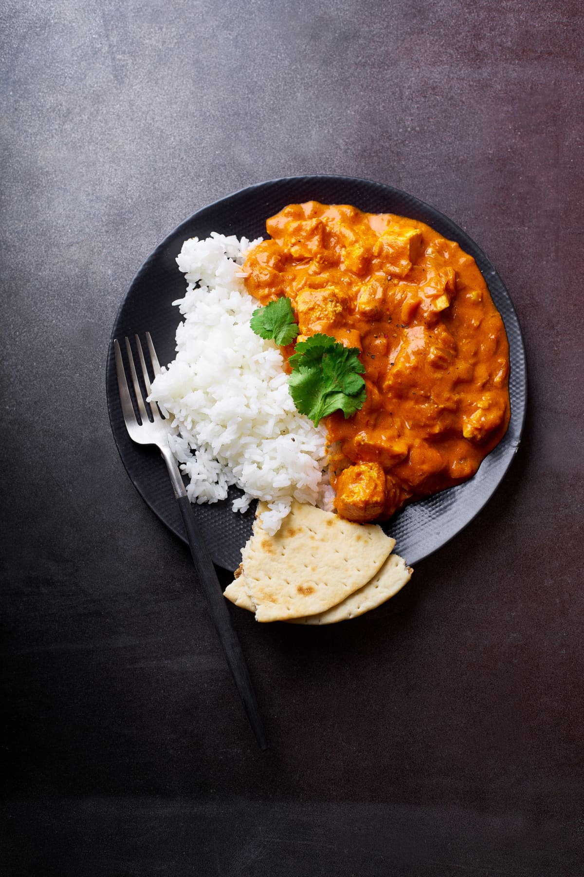 Creamy butter chicken curry with wooden spoon in pot