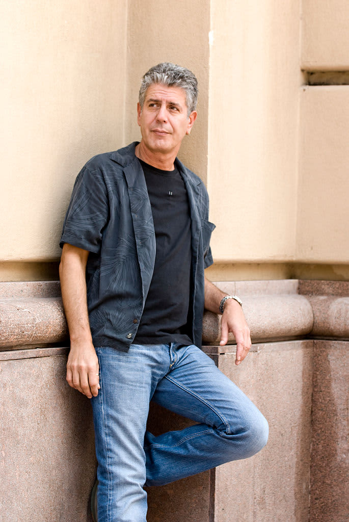 Anthony Bourdain seated and holding his book