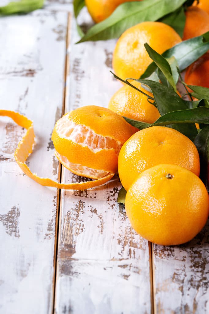 Ripe organic clementines or tangerines with leaves over white wooden plank table as background. Close up, space. Healthy eating. (Photo by: Natasha Breen/REDA&CO/Universal Images Group via Getty Images)