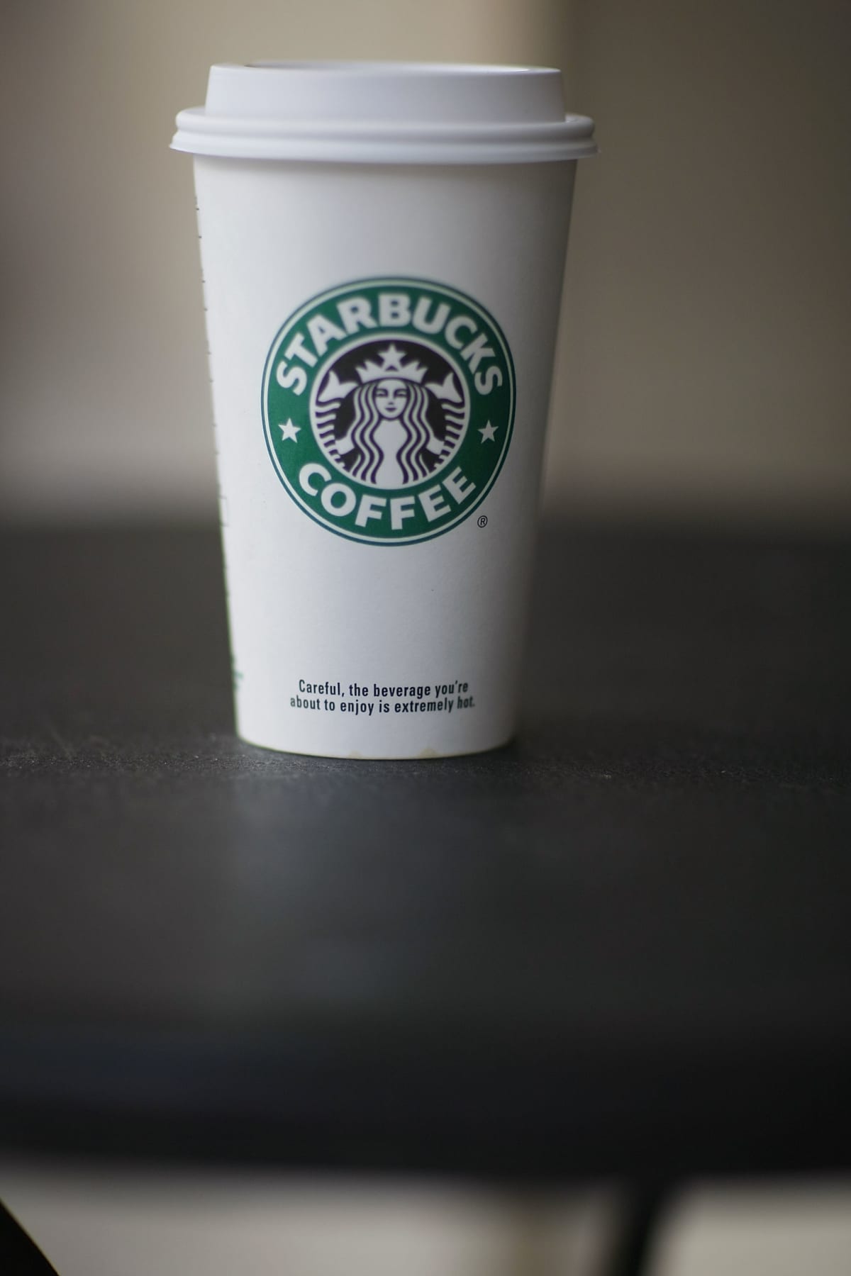 A Starbucks "Grande" 16oz Coffee with a Bran Muffin. Shot in a photography studio on a wood table.