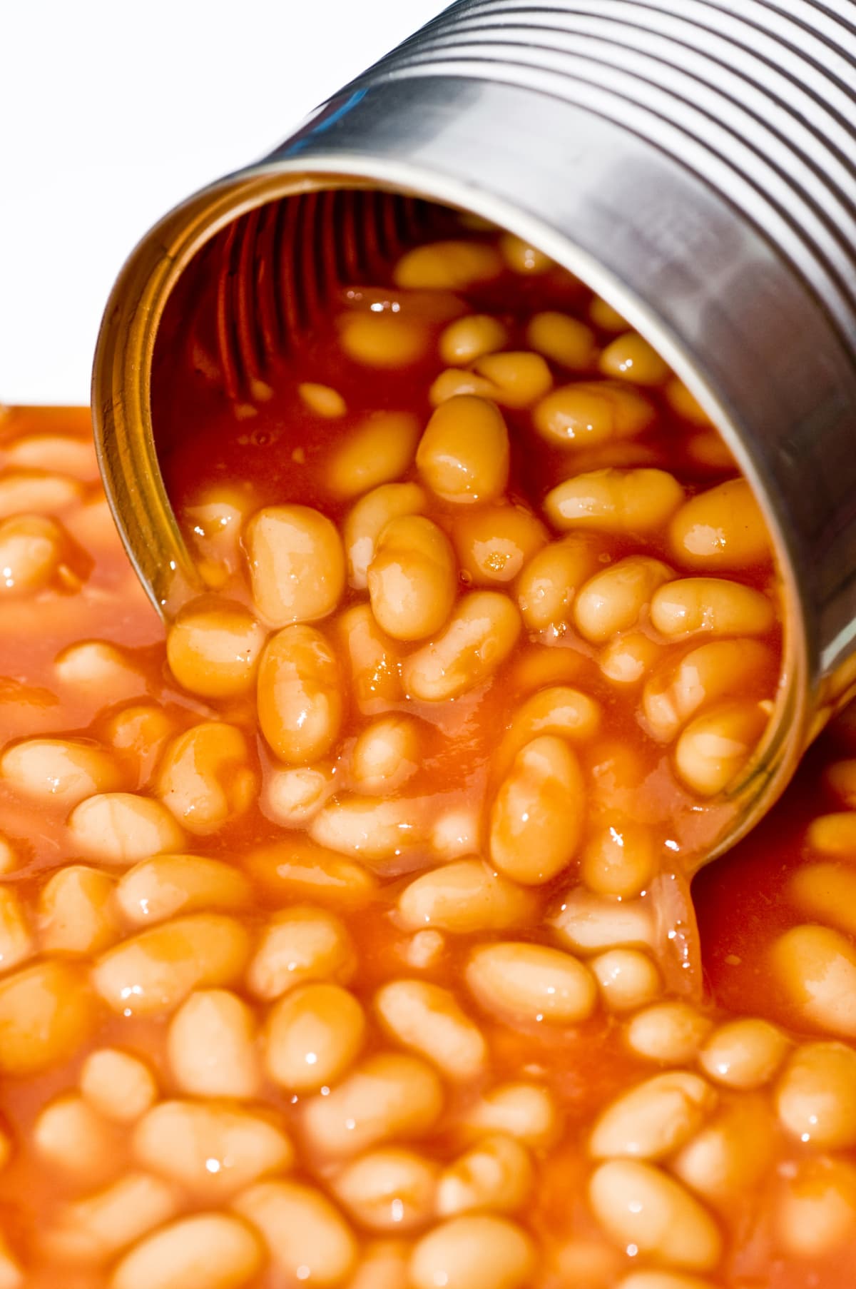 An opened can of baked beans spilling over