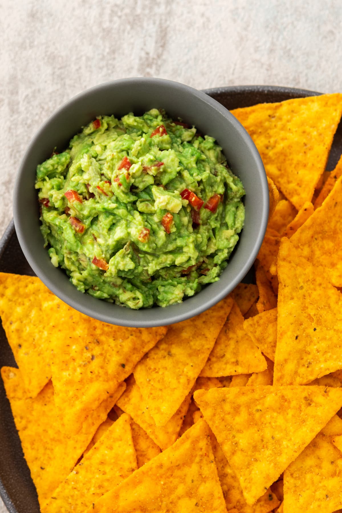 Mexican corn chips nachos with avocado red pepper sauce, top view