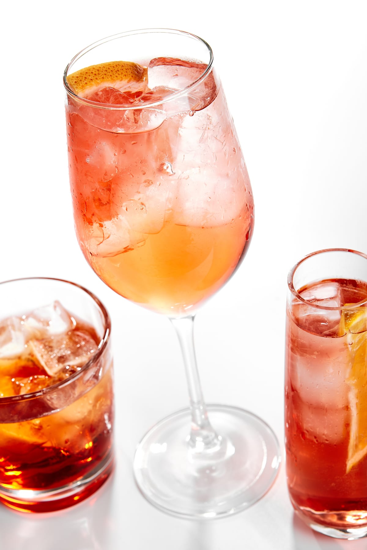 Three orange cocktails with citrus and ice
