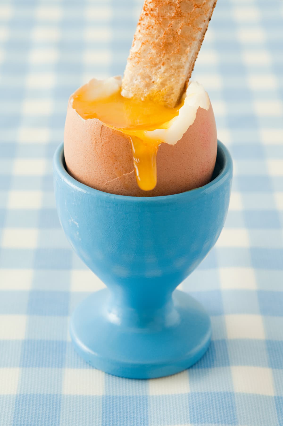 Soft-boiled egg in an egg cup on tablecloth