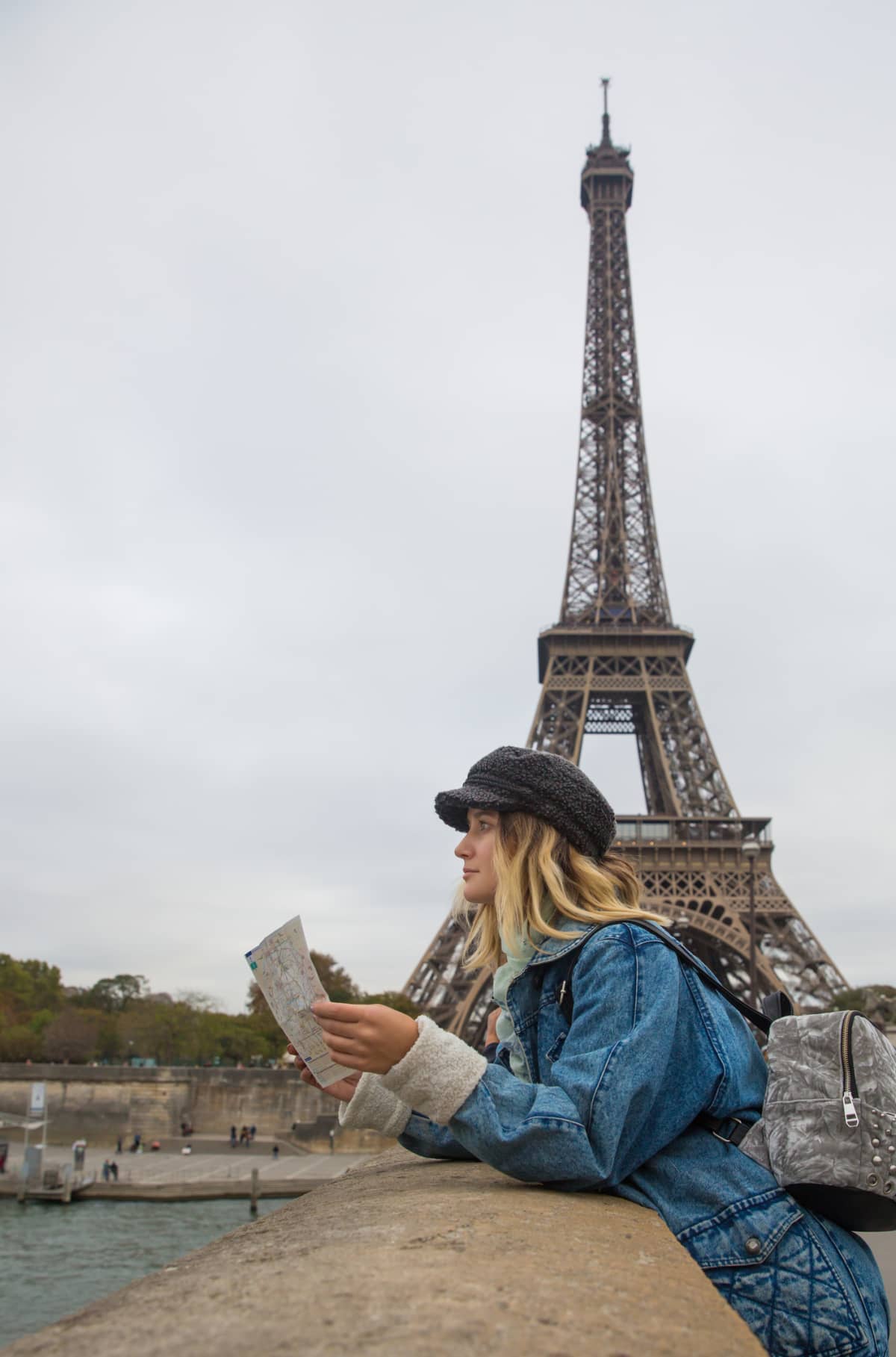 Young woman in Paris, France looking at map or city guide. Travel and people concept.